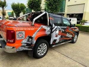 A pickup truck with "Home Demolitions" branding and a QR code is parked outside a building, ready for action. It's the perfect companion for specialized tasks, from structural teardowns to niche services like air conditioner degassing.